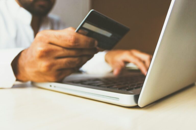 Person mit Kreditkarte am Laptop beim Online-Einkauf